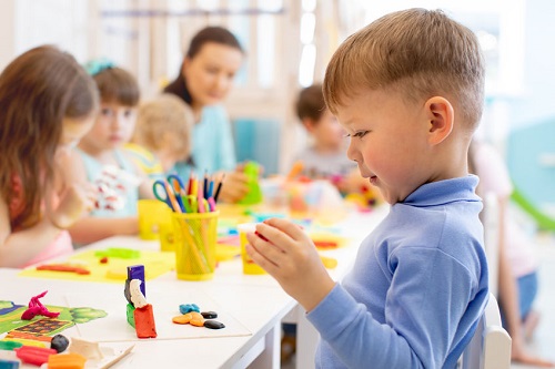 Enfant garçon et groupe d'enfants travaillant avec des jouets en argile colorée en crèche. Moulage créatif d'enfants à la maternelle. Les enfants d'âge préscolaire jouent avec de la pâte à modeler ou de la pâte.