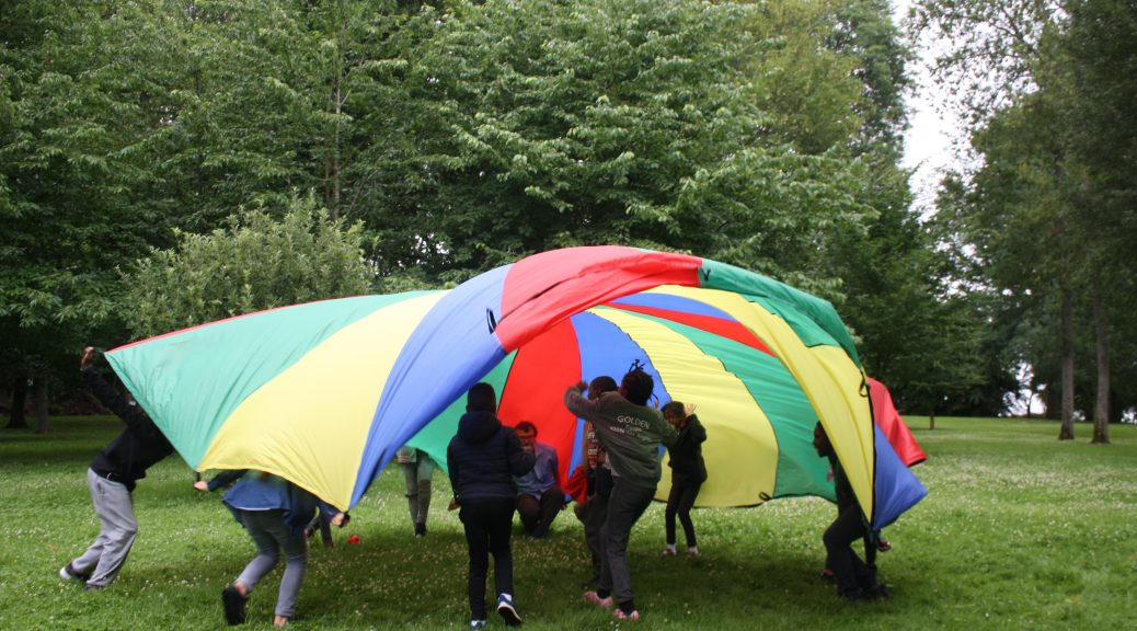 des enfants et leur animateur jouent avec un parachute.